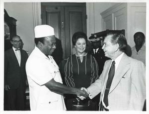 Carl Albert shaking hands with William R. Tolbert, Jr. (President of Liberia). Shirley Temple Black is in the background. September 23, 1976, 1976-09-23