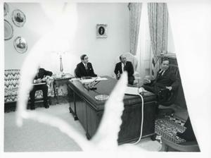 Carl Albert seated at his desk and talking with unidentified men seated beside him during the Korean-U.S. Interparliamentary Conference. July 22-23, 1973, 1973-07-22