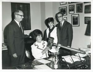 Charles Ward and Mike Reed with two unidentified woman at Carl Albert&#39;s desk., 1950-01-01 - 1976-12-31