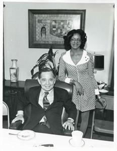 Carl Albert sitting at his desk, with Loise Butler standing next to him., 1950-01-01 - 1976-12-31