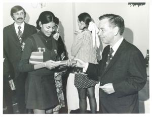 Loise Butler, Polly Ritter, Carl Albert and others at office Christmas Party. Albert is giving Butler a gift. 1971, 1971-12-01