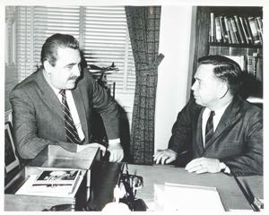 Carl Albert seated and talking with an unidentified man at his desk., 1950-01-01 - 1976-12-31