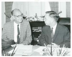 Carl Albert seated at his desk and talking with Jim Robinson. September 1, 1966, 1966-09-01