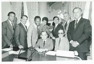 Carl Albert with Andrew Young and Hank Aaron and others posing behind Albert&#39;s desk., 1950-01-01 - 1976-12-31