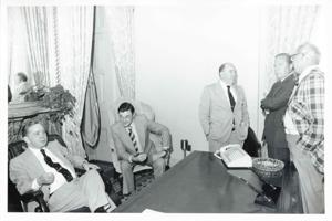 Carl Albert seated at his desk. John Rhodes and others are standing around the desk., 1950-01-01 - 1976-12-31