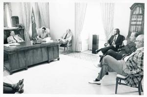 Carl Albert seated at his desk. Several men are seated around the desk., 1950-01-01 - 1976-12-31