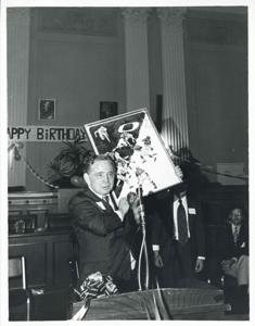 Carl Albert holding up his new portrait of Oklahoma football on his birthday. 1976, 1976-05-10