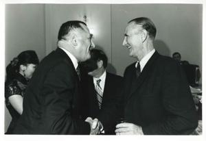 Mike Mansfield shaking hands with an unidentified man at Carl Albert&#39;s birthday party. May 10, 1974, 1974-05-10