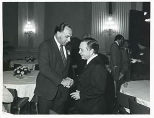 Carl Albert shaking hands with an unidentified man at a reception for freshman members of the 94th Congress. December 1, 1975 Thomas P. O&#39;Neill is present in 3077, 1975-12-01