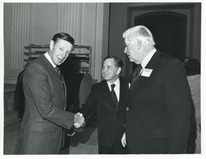 Carl Albert shaking hands with an unidentified man at a reception for freshman members of the 94th Congress. December 1, 1975 Thomas P. O&#39;Neill is present in 3077, 1975-12-01