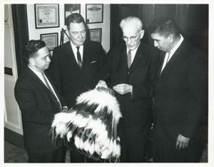Carl Albert, Hale Boggs, John W. McCormack, and another man standing together. They are looking at an Indian headdress., 1950-01-01 - 1976-12-31