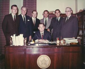 Carl Albert seated at his desk. Behind him standing L to R are: Jed Johnson, Jr., A. S. Mike Monroney, Ed Edmondson, John Jarman, Fred Harris, and Tom Steed., 1950-01-01 - 1976-12-31