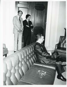 Carl Albert seated on a couch. Two unidentified men are standing in the background, 1950-01-01 - 1976-12-31