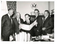 Carl Albert viewing a booklet dealing with Talimena Scenic Drive with two unidentified men, 1950-01-01 - 1976-12-31