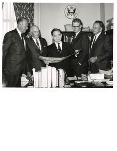 Carl Albert viewing a booklet dealing with Talimena Scenic Drive, with four unidentified men, 1950-01-01 - 1976-12-31