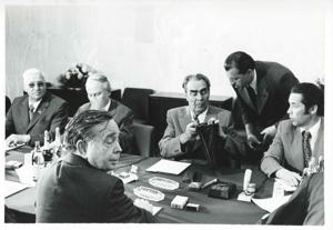 Carl Albert, Leonid Brezhnev, and other men seated at a table. House delegation trip. August 1975, 1975-08-04