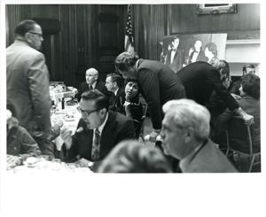 Carl Albert (center), Alan Cranston (behind Albert), and Roz Wyman looking at a scrapbook/photo album at a luncheon., 1970-01-01 - 1976-12-31