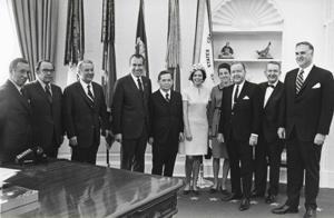 Carl Albert, Richard M. Nixon, and Henry Bellmon visit with a small boy who is on crutches. Another boy and perhaps the parents are in the background. May 1969 Photo is autographed by Nixon and carries the inscription To Congressman Carl Albert with appreciation for his service to the country and with best wishes. Oversized., 1969-05-01