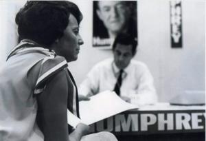 LaDonna Harris (foreground) with Fred R. Harris seated behind a desk, 1963-01-01 - 1976-12-31