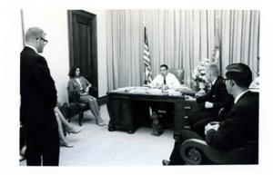 Fred R. Harris at his desk There are several unidentified people in his office, 1963-01-01 - 1976-12-31